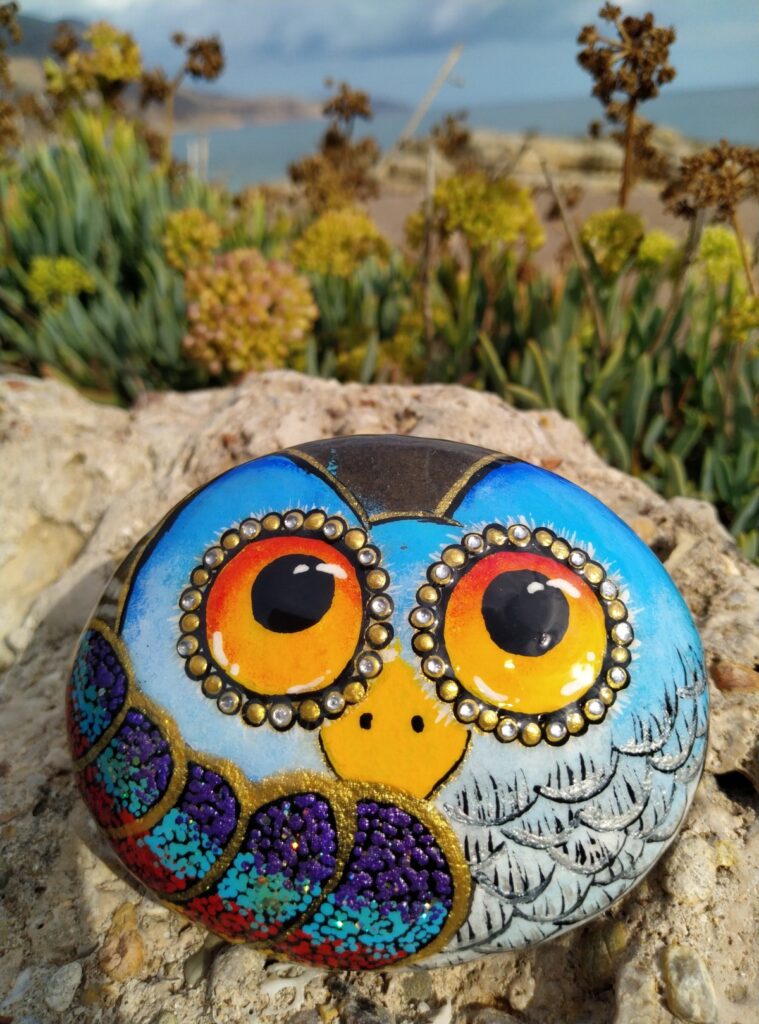 Colorful owl painted on stone placed on a rock in Kissamos