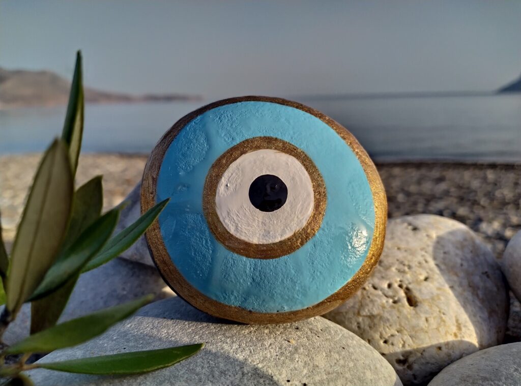 light colored evil eye painted on stone placed near the sea