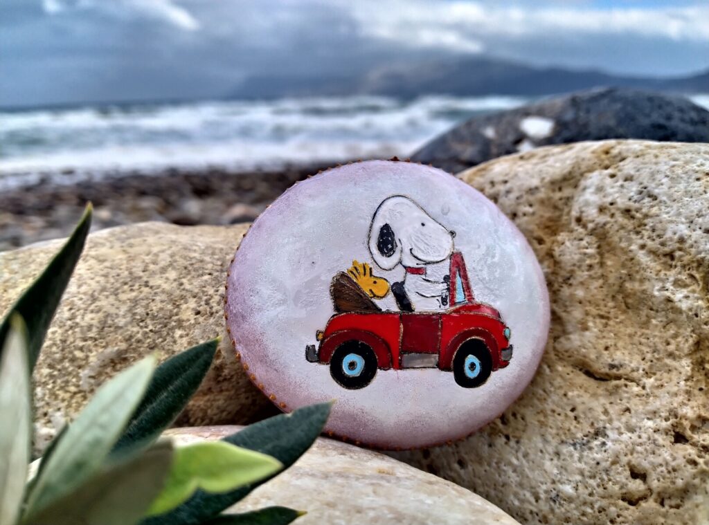 Snoopy driving a car painted on stone