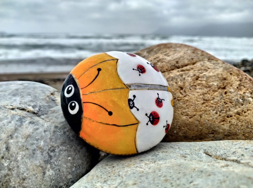 Yellow ladybug with other small ladybugs painted on stone placed near kissamos beach